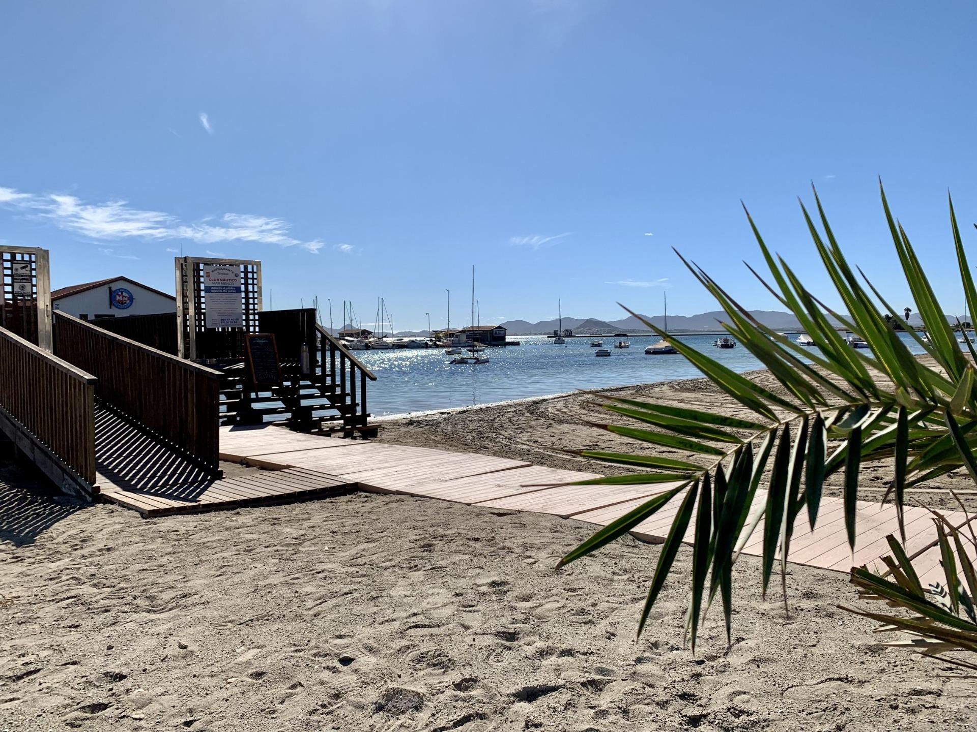 Sandy beach with clear blue sky and calm sea near exclusive new build villas in Los Alcázares, Murcia.