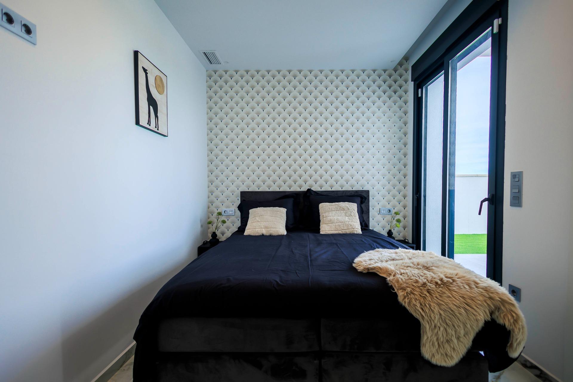 Bright modern bedroom with plush bed and textured accent wall in new build villa Pilar de la Horadada golf course