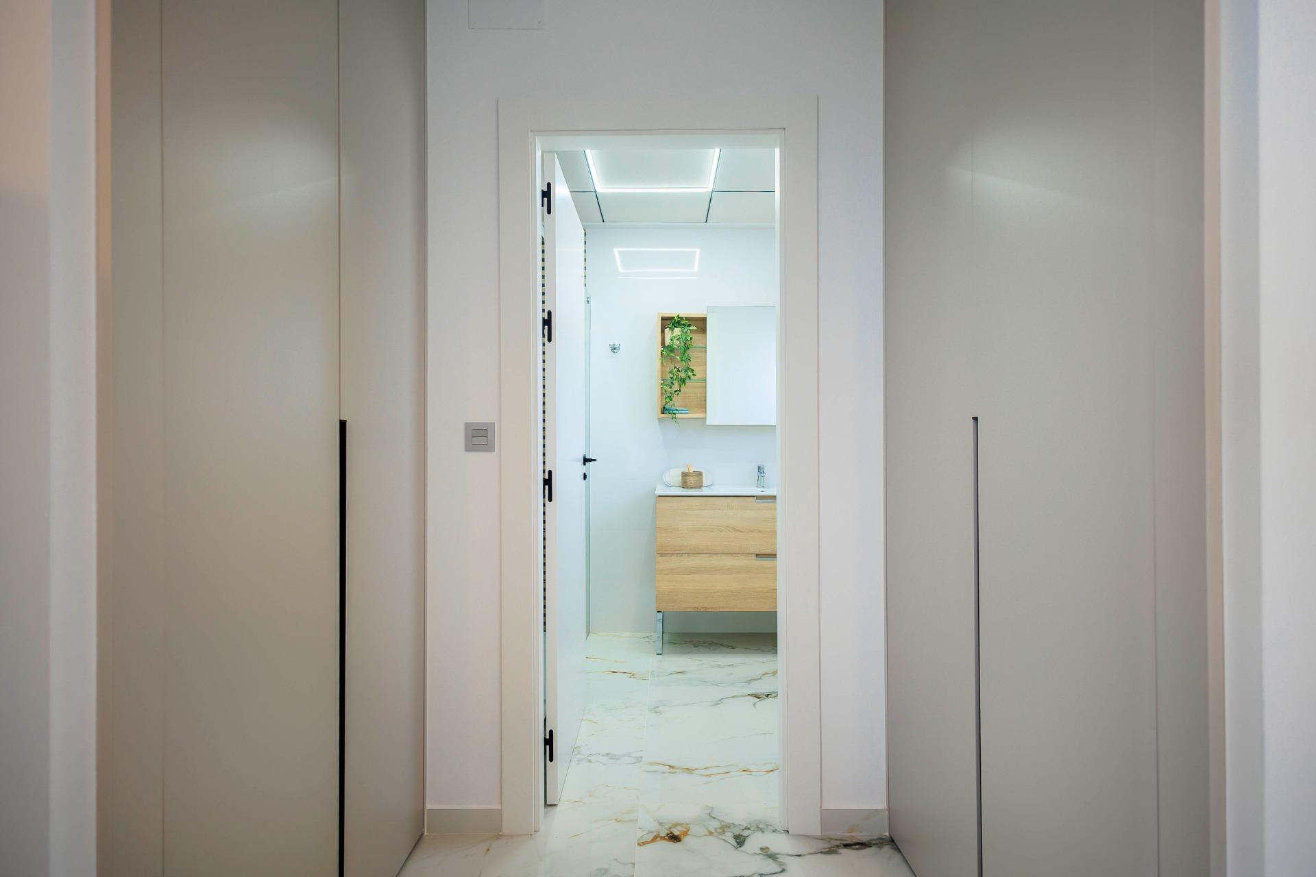 Bright modern hallway with sleek storage leading to an elegant bathroom in new build villas in Pilar de la Horadada golf course