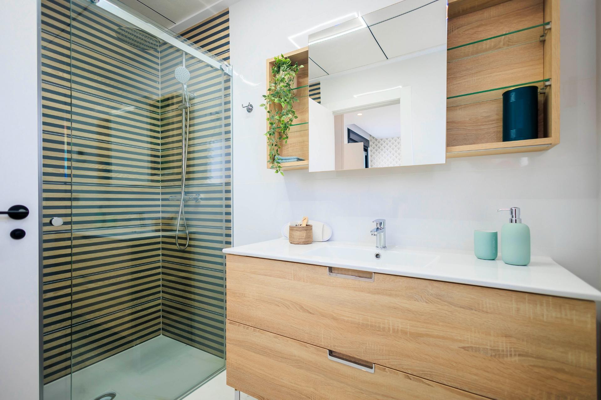 Modern bright bathroom with sleek glass shower and wooden vanity in new build villas in Pilar de la Horadada.