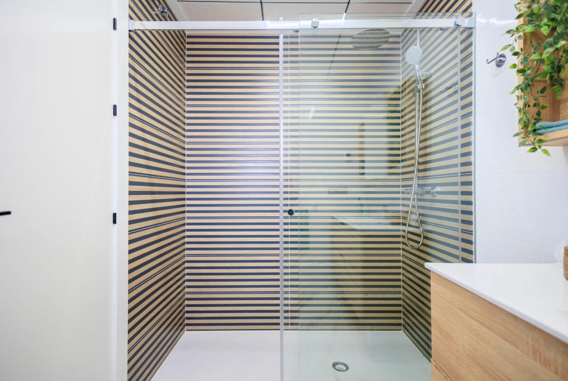 Modern, sleek shower with striped wood paneling and glass enclosure in luxury new build villa bathroom in Pilar de la Horadada