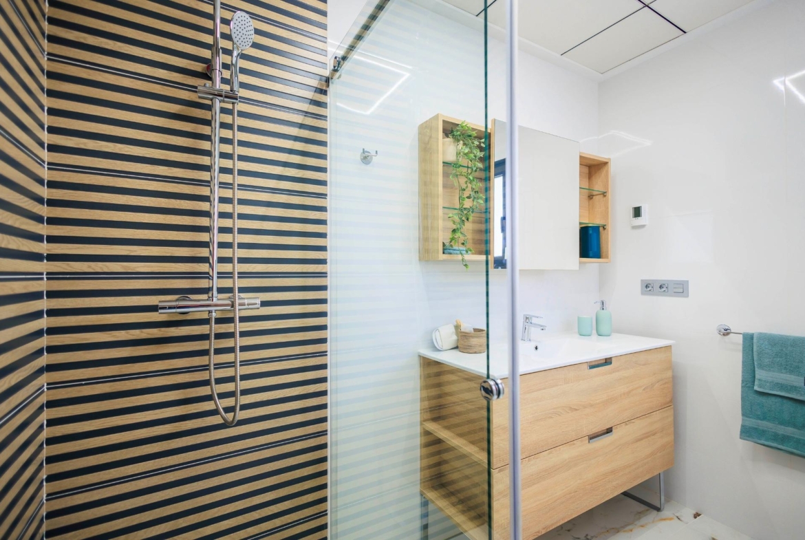 Modern, bright bathroom with sleek wooden vanity and glass shower in new build villas in Pilar de la Horadada on the golf course