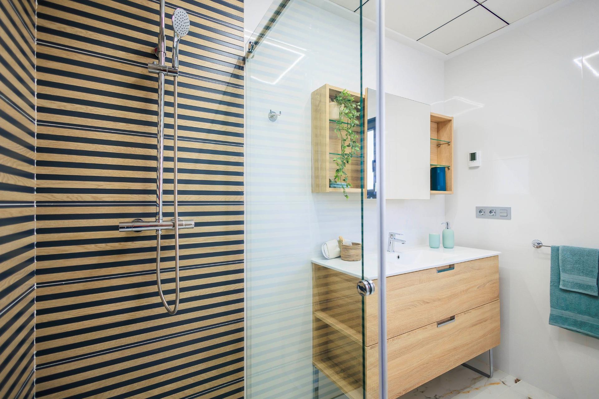 Modern, bright bathroom with sleek wooden vanity and glass shower in new build villas in Pilar de la Horadada on the golf course