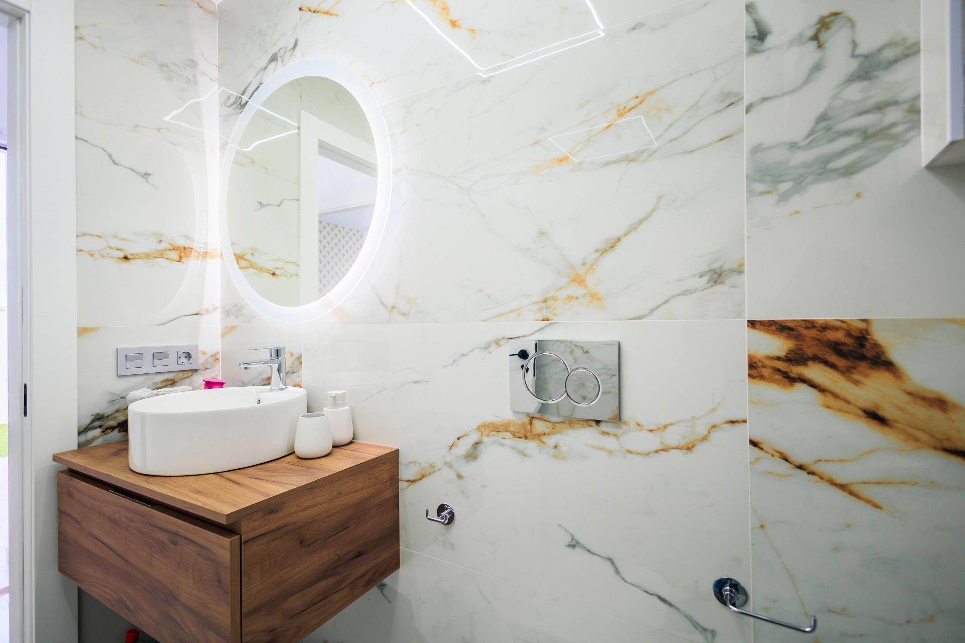 NEW-BUILD-VILLAS-IN-PILAR-DE-LA-HORADADA-ON-THE-GOLF-COURSE-19 Elegant modern bathroom with marble walls and wooden vanity in new build villas on the golf course in Pilar de la Horadada