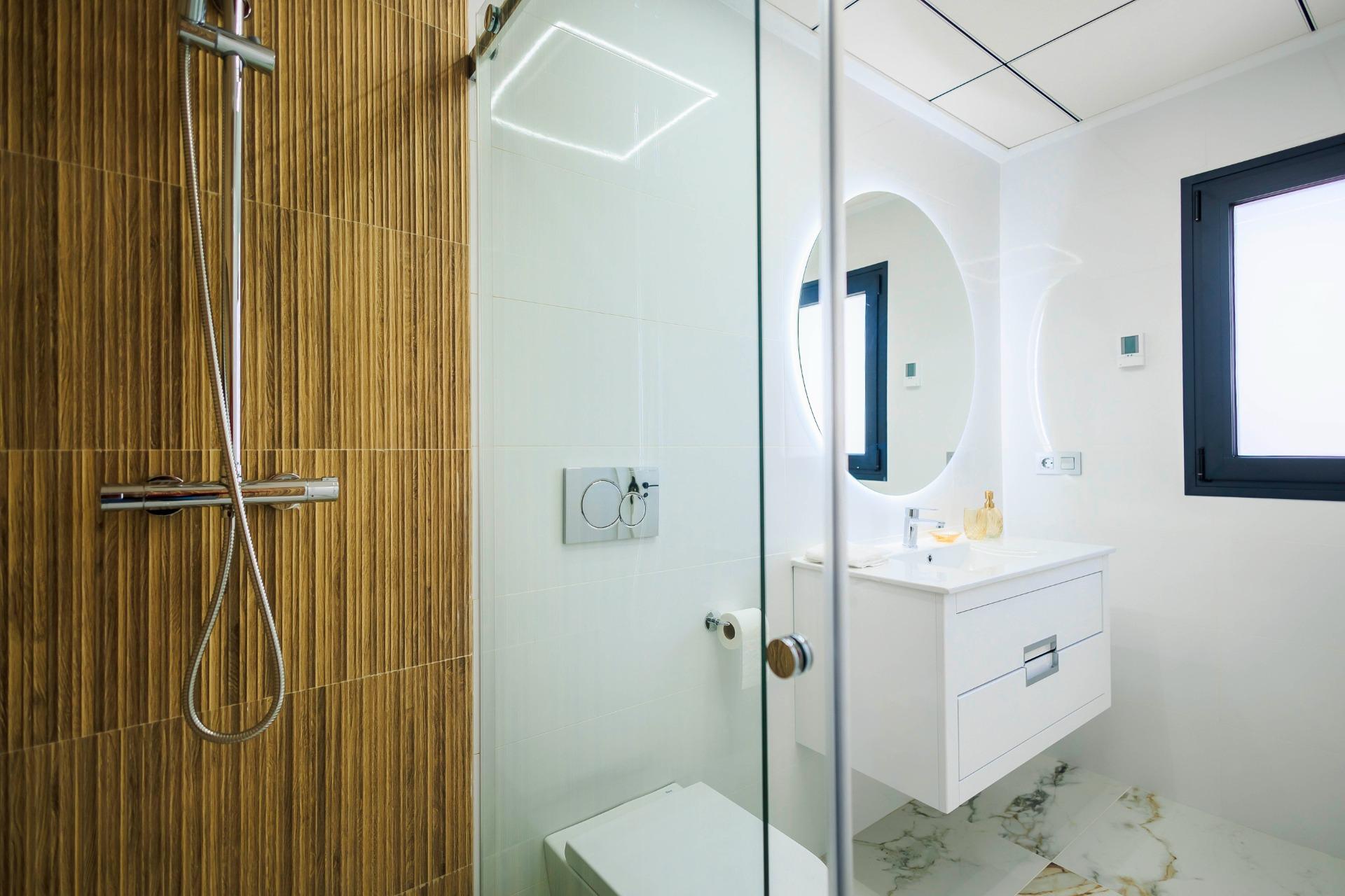 Modern luxury bathroom with sleek wood-paneled shower, bright vanity, and marble flooring in new Pilar de la Horadada golf villas.