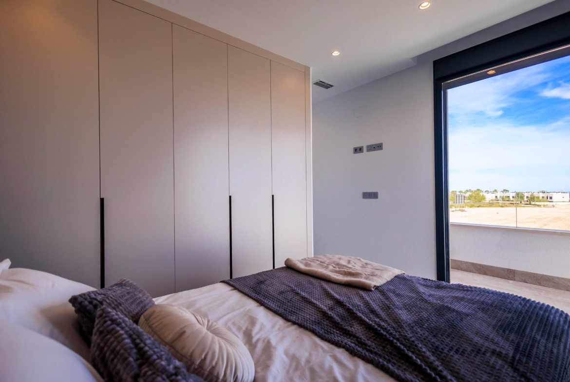 Bright modern bedroom with built-in wardrobes and balcony in luxury new build villas in Pilar de la Horadada on the golf course