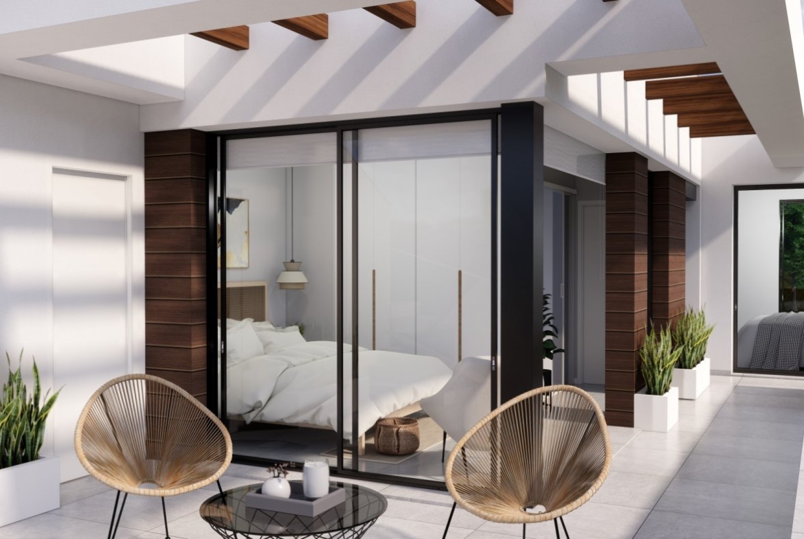 NEW-BUILD-VILLAS-IN-PILAR-DE-LA-HORADADA-ON-THE-GOLF-COURSE-3 Sun-drenched terrace with modern rattan chairs and sliding glass doors leading to a bedroom in new build villas in Pilar de la Horadada on the golf course