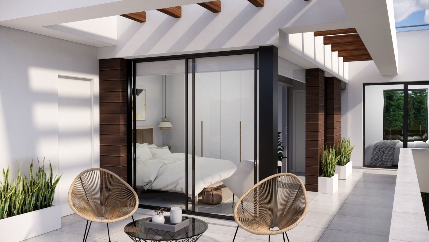 NEW-BUILD-VILLAS-IN-PILAR-DE-LA-HORADADA-ON-THE-GOLF-COURSE-3 Sun-drenched terrace with modern rattan chairs and sliding glass doors leading to a bedroom in new build villas in Pilar de la Horadada on the golf course