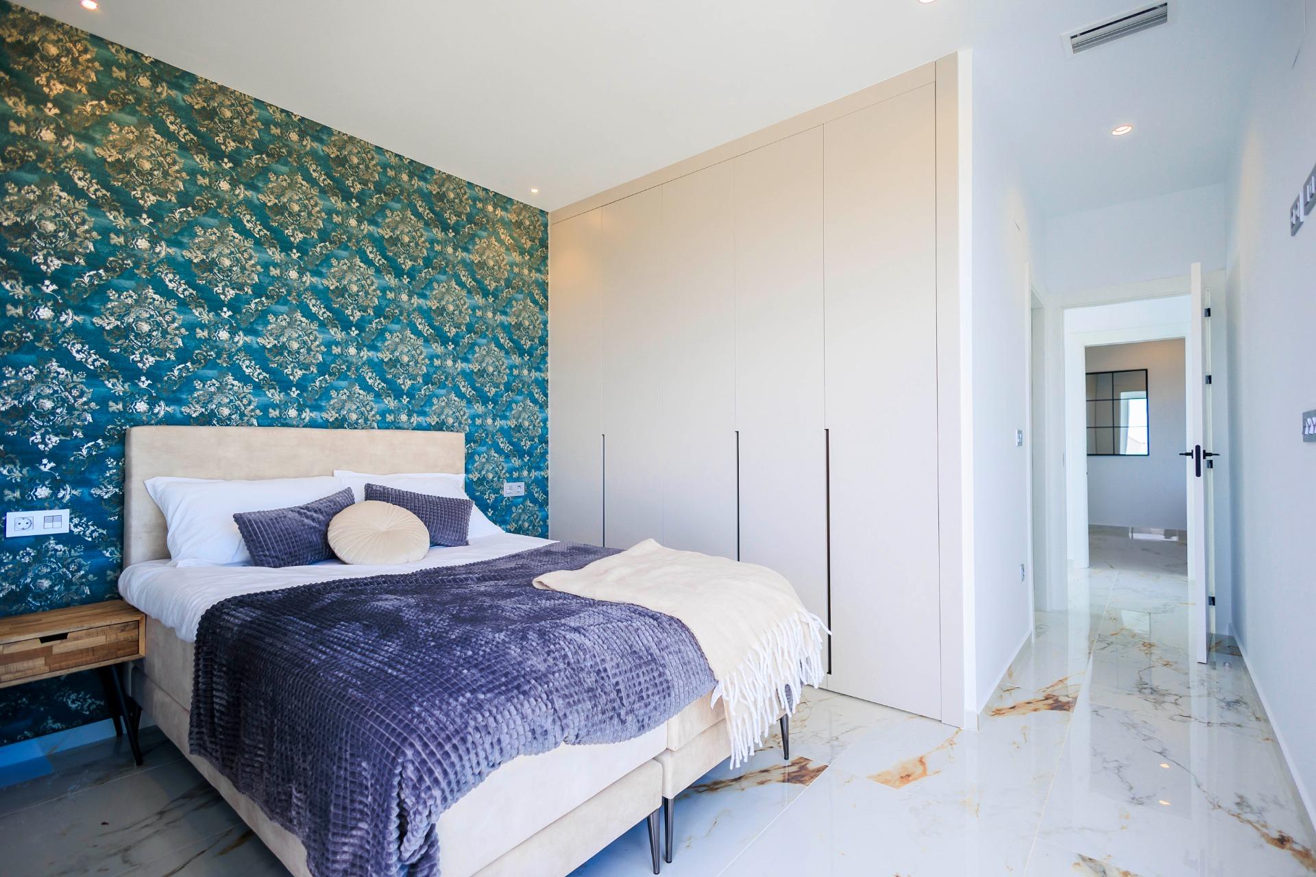 Bright and elegant bedroom with patterned feature wall and marble flooring in new build villas in Pilar de la Horadada on the golf course.