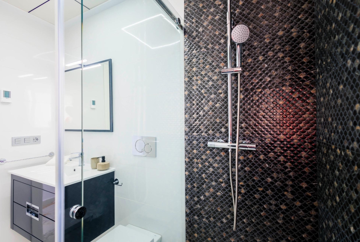 NEW-BUILD-VILLAS-IN-PILAR-DE-LA-HORADADA-ON-THE-GOLF-COURSE-34 Modern elegant bathroom with sleek fixtures and textured dark tile wall in new build villas in Pilar de la Horadada on the golf course