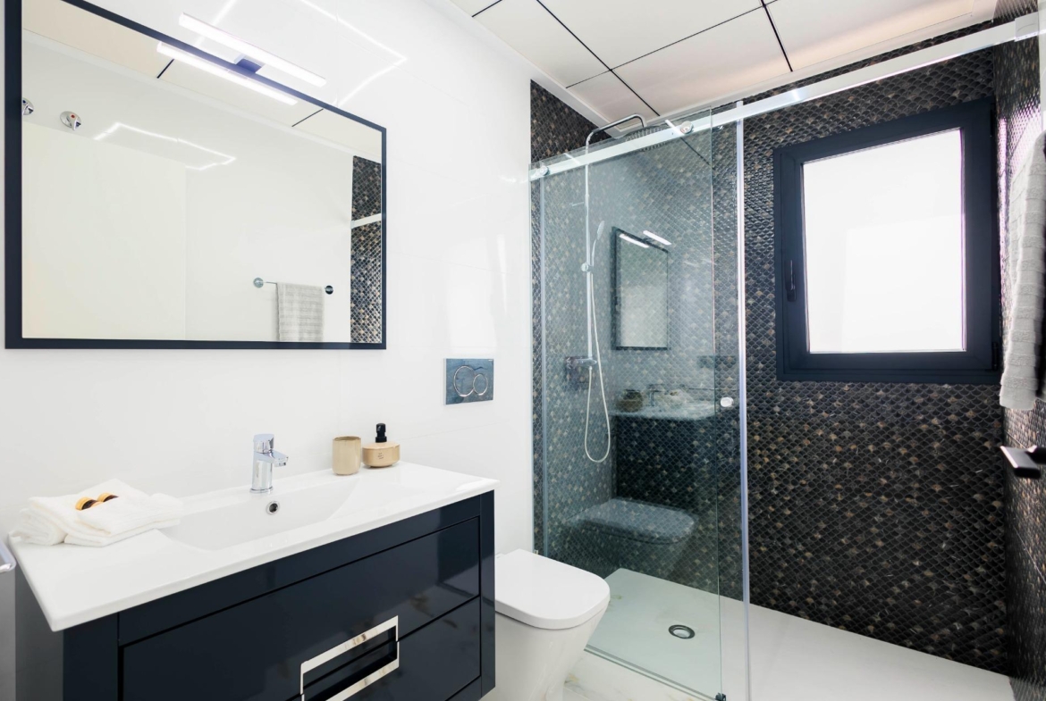 Modern, sleek bathroom with walk-in shower and elegant dark tile accents in luxury new build villas in Pilar de la Horadada on the golf course