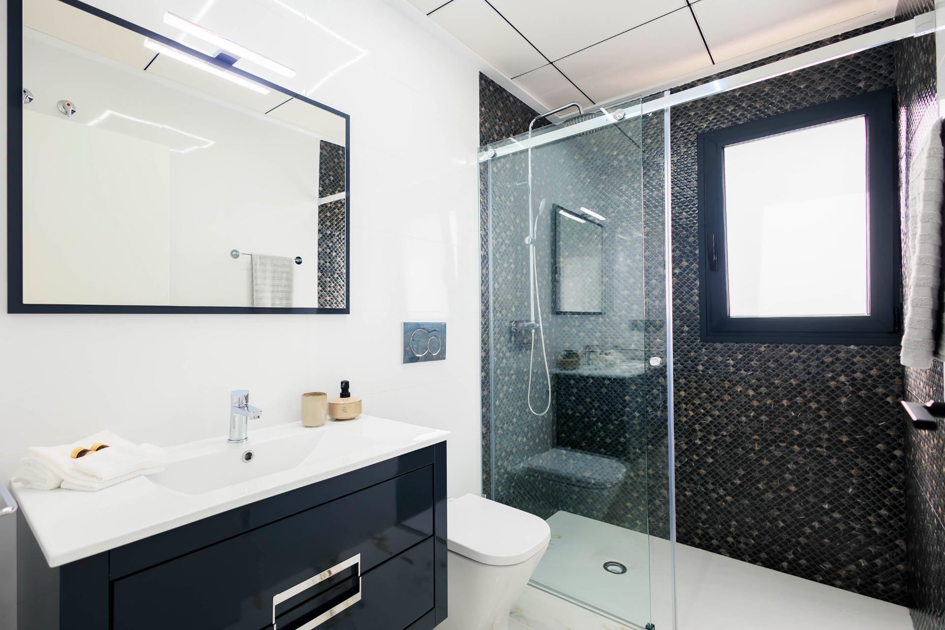 Modern, sleek bathroom with walk-in shower and elegant dark tile accents in luxury new build villas in Pilar de la Horadada on the golf course