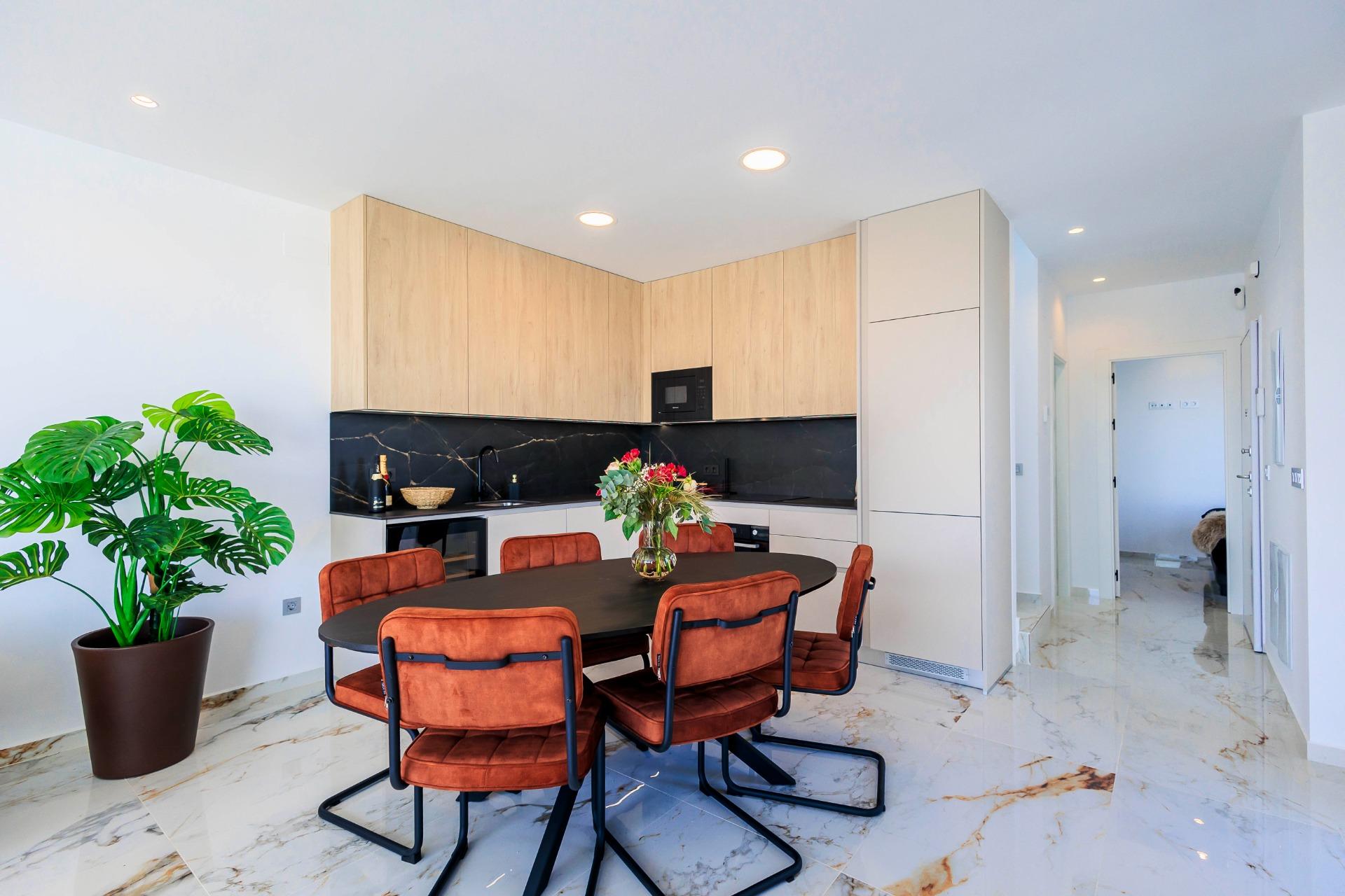 NEW-BUILD-VILLAS-IN-PILAR-DE-LA-HORADADA-ON-THE-GOLF-COURSE-37 Modern open-plan kitchen and dining area with sleek cabinetry and marble floors in new Pilar de la Horadada golf course villas