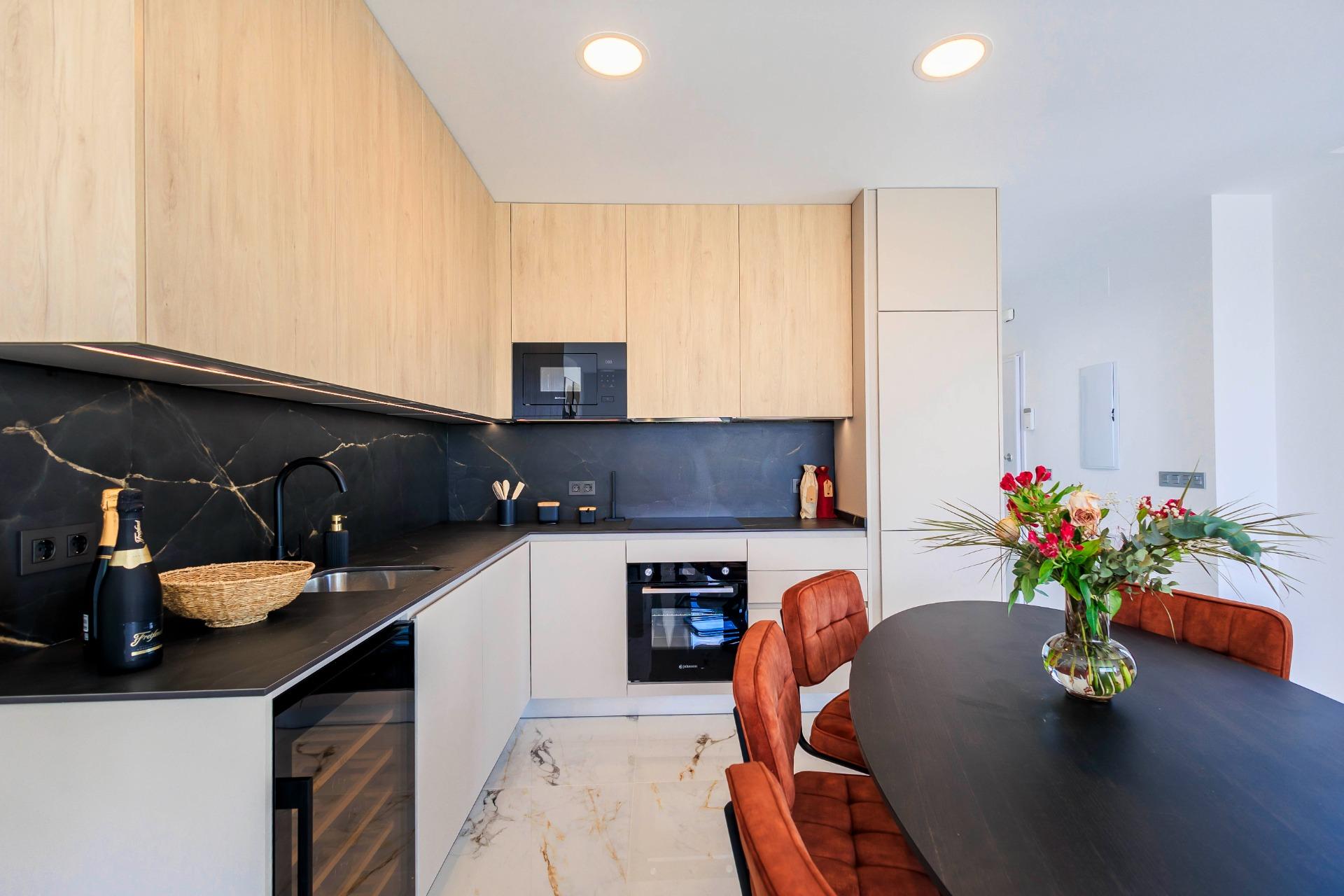 NEW-BUILD-VILLAS-IN-PILAR-DE-LA-HORADADA-ON-THE-GOLF-COURSE-38 Modern, bright kitchen and dining area with sleek black countertops and warm wood cabinetry in new Pilar de la Horadada golf course villas.