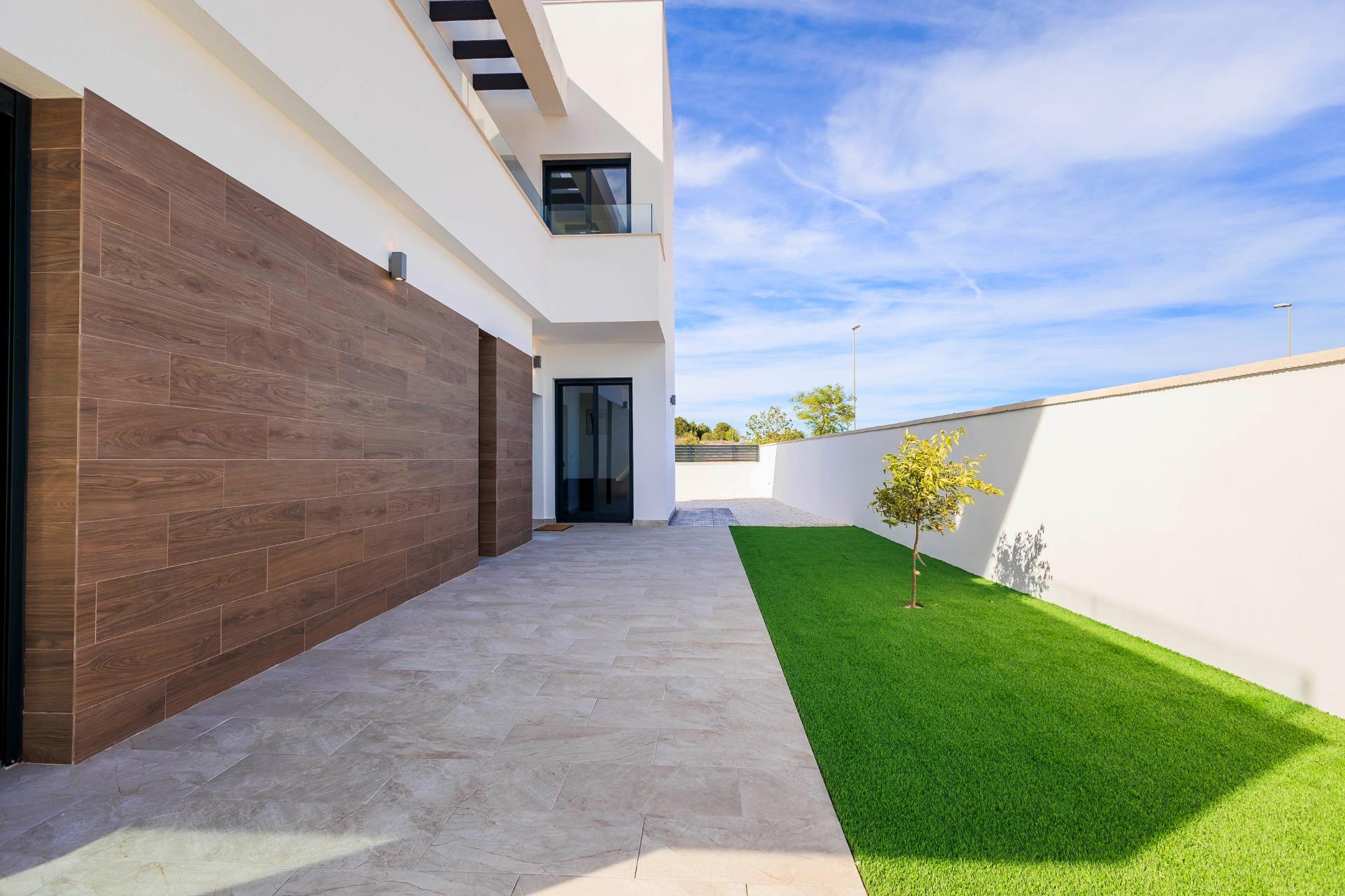 Modern new build villa exterior in Pilar de la Horadada featuring sleek wooden accents and a bright landscaped terrace.