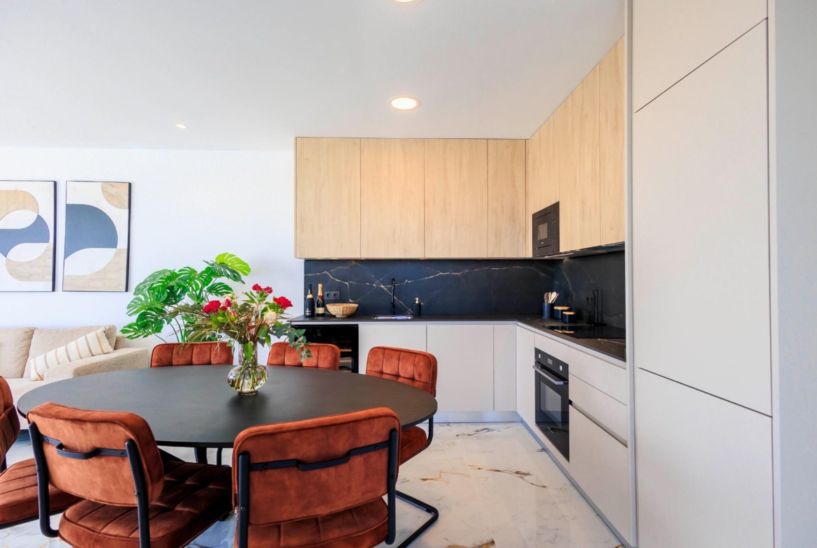Modern open-plan kitchen and dining area with sleek cabinetry and stylish seating in new build villas in Pilar de la Horadada.