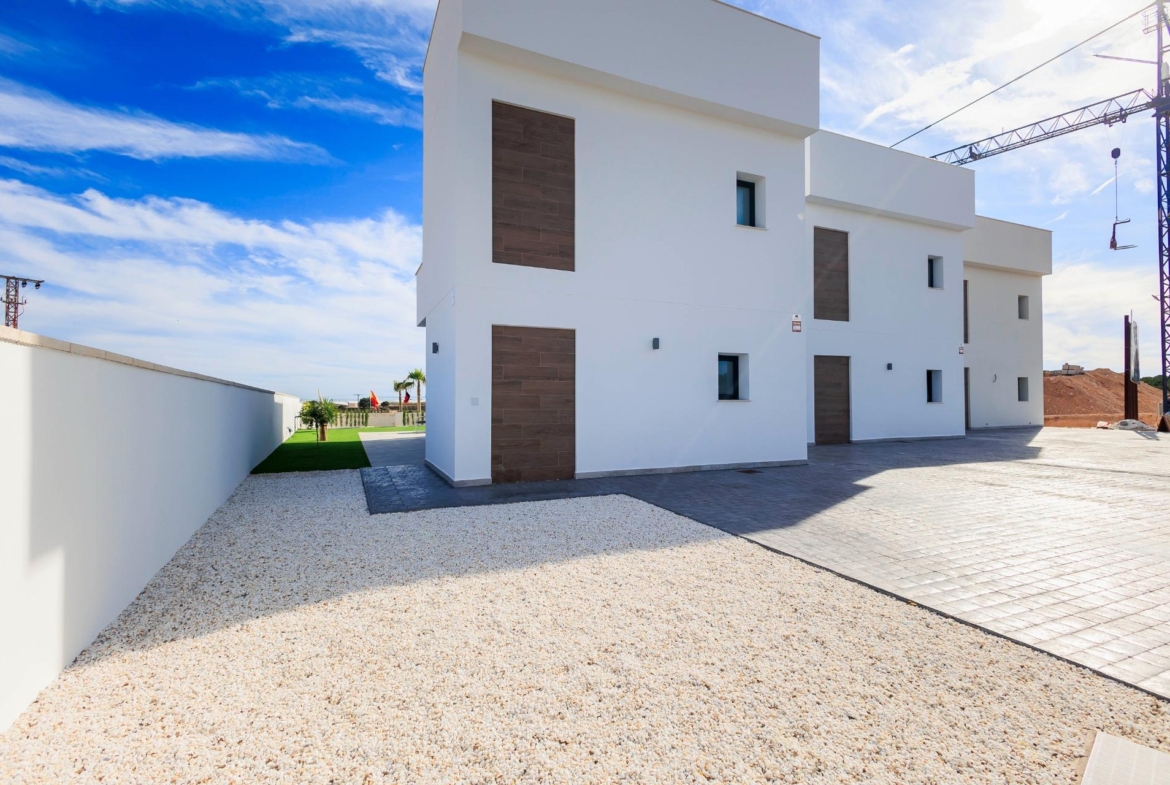 NEW-BUILD-VILLAS-IN-PILAR-DE-LA-HORADADA-ON-THE-GOLF-COURSE-45 Modern white façade of new build villas in Pilar de la Horadada with spacious driveway and bright blue sky backdrop