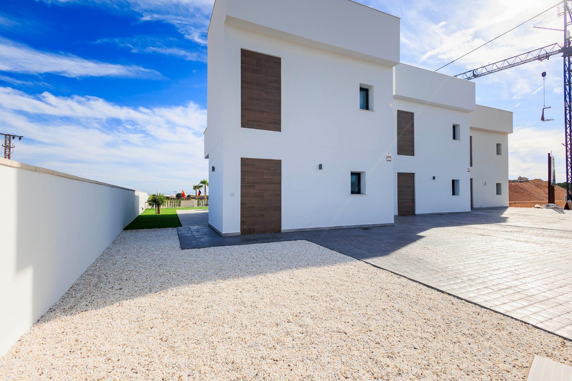 NEW-BUILD-VILLAS-IN-PILAR-DE-LA-HORADADA-ON-THE-GOLF-COURSE-45 Modern white façade of new build villas in Pilar de la Horadada with spacious driveway and bright blue sky backdrop