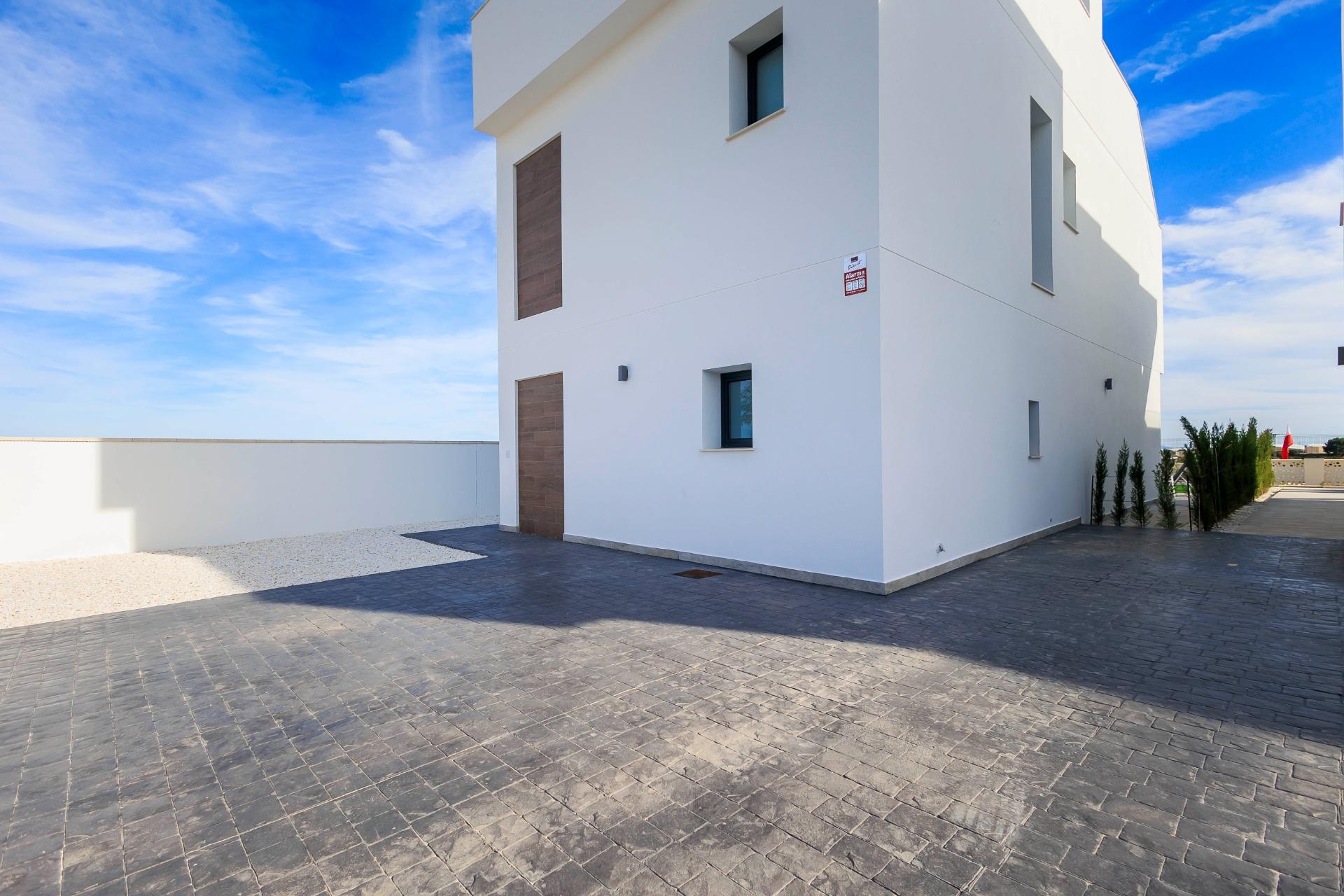 NEW-BUILD-VILLAS-IN-PILAR-DE-LA-HORADADA-ON-THE-GOLF-COURSE-46 Modern new build villa exterior in Pilar de la Horadada with sleek white facade and spacious paved driveway
