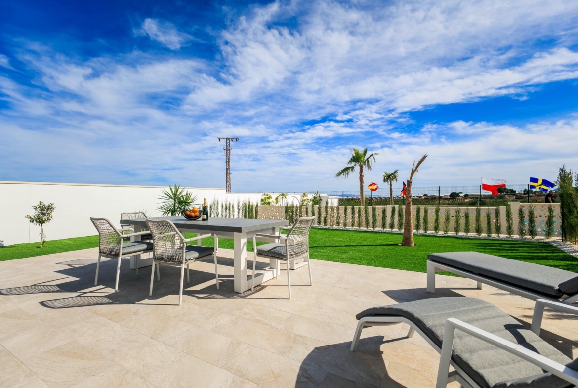 Sun-drenched modern terrace with elegant outdoor dining and loungers at new build villas in Pilar de la Horadada golf course