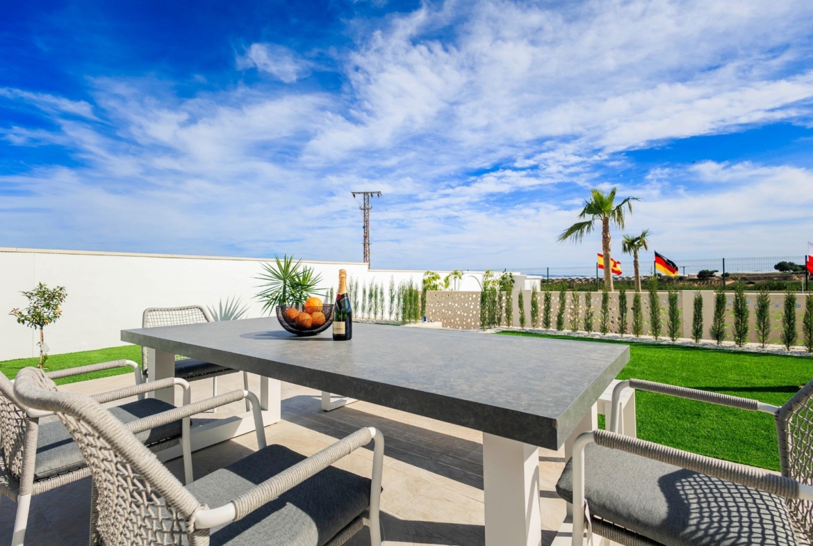 Modern outdoor terrace with stylish dining set and landscaped garden at new build villas in Pilar de la Horadada golf course