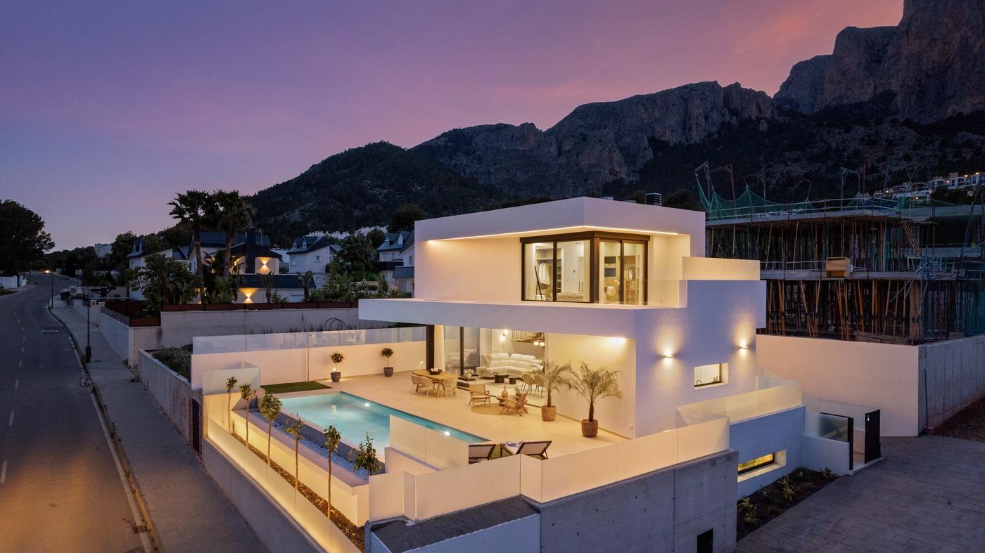 Modern sunlit 3-bedroom villa in Polop, Costa Blanca with private illuminated pool and mountain backdrop at dusk.