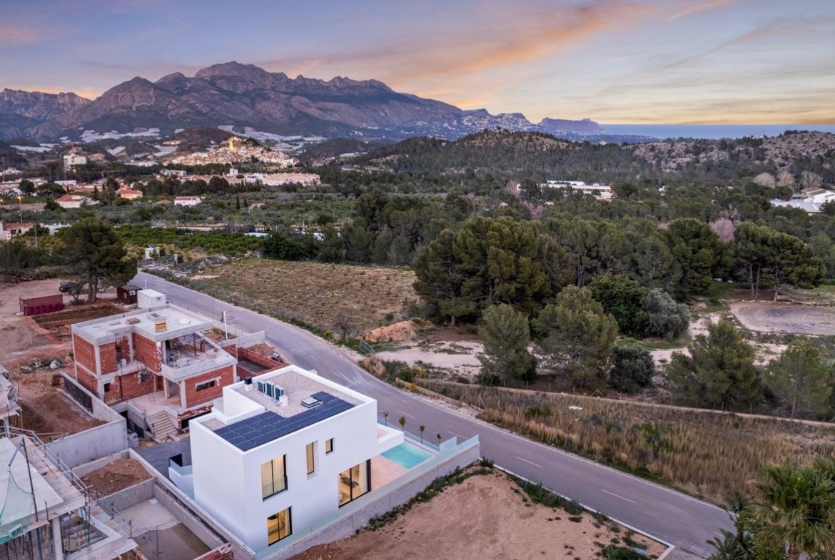 Modern white 3-bedroom villa with private pool and solar panels set in tranquil landscape near Polop, Costa Blanca at sunset.