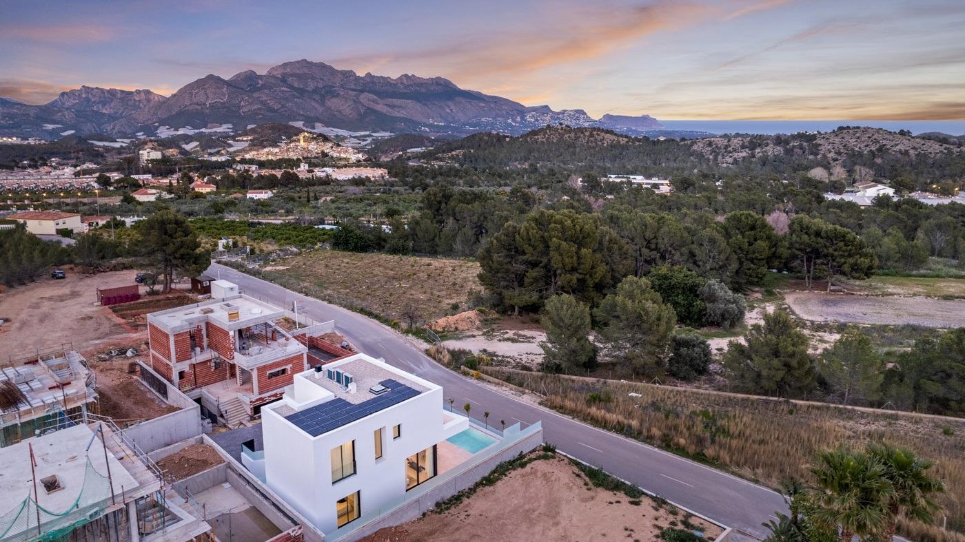 Modern white 3-bedroom villa with private pool and solar panels set in tranquil landscape near Polop, Costa Blanca at sunset.