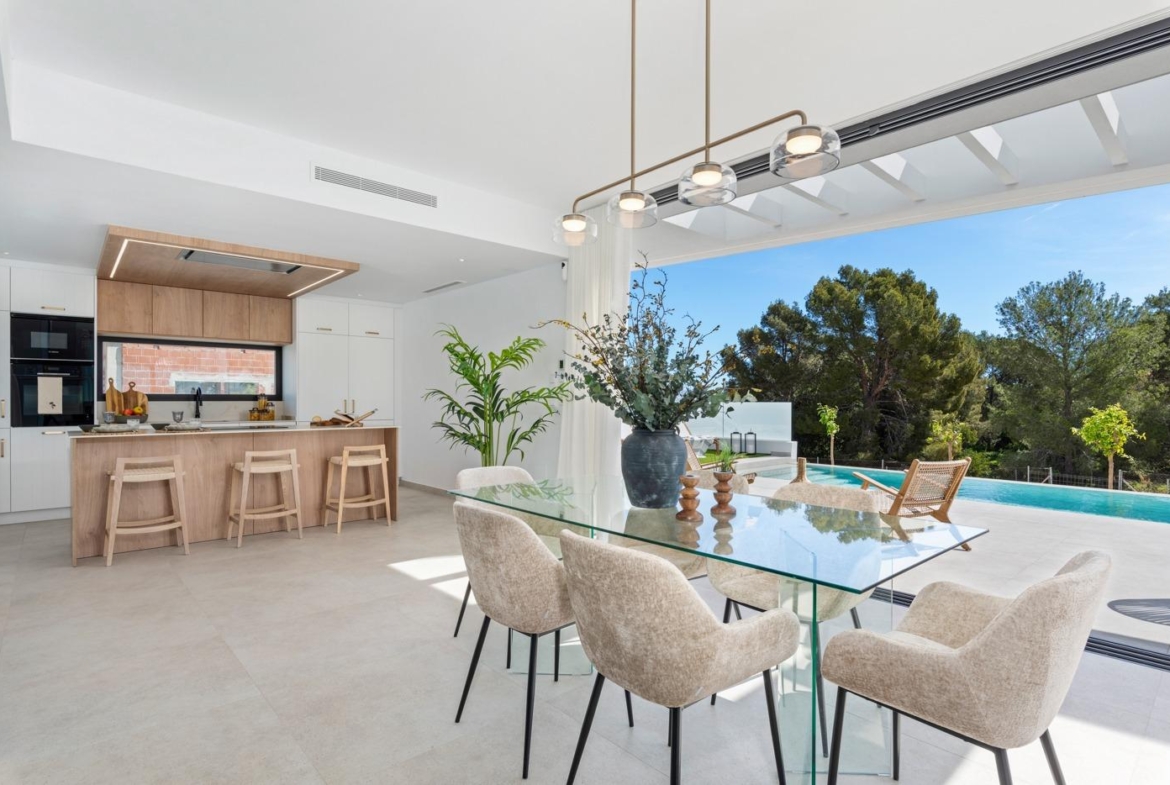 Bright open-plan kitchen and dining area with sleek modern furnishings and views of a private pool in luxury 3-bedroom villa in Polop, Costa Blanca.