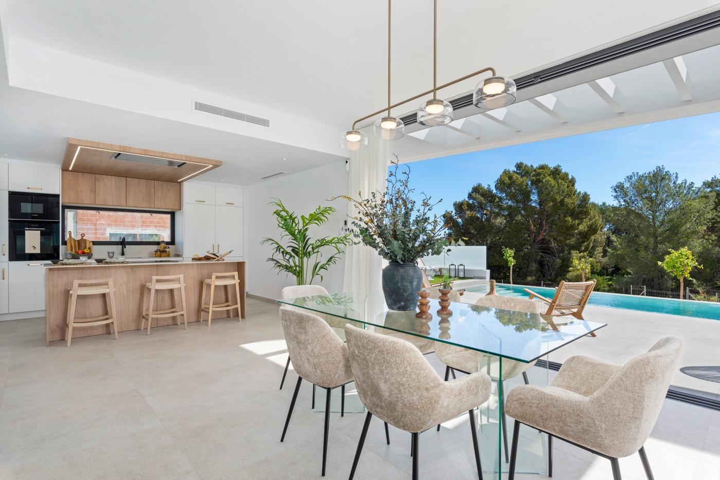 Bright open-plan kitchen and dining area with sleek modern furnishings and views of a private pool in luxury 3-bedroom villa in Polop, Costa Blanca.