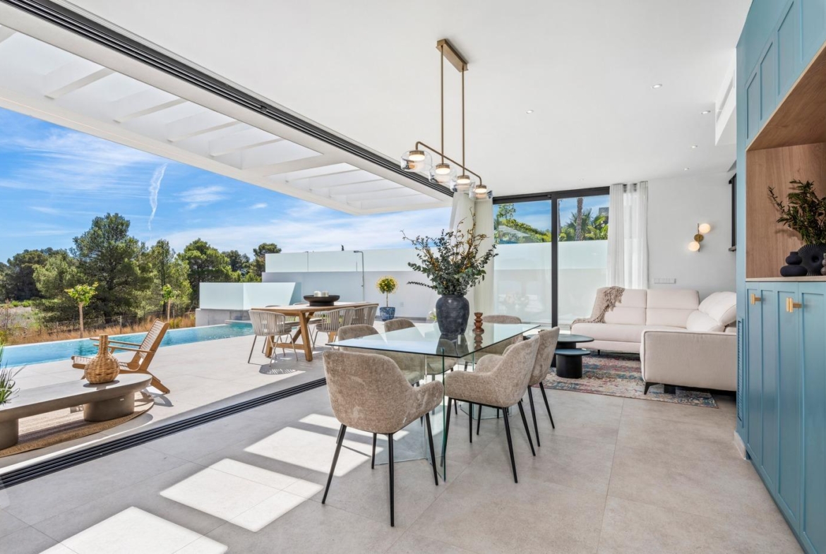Sun-drenched open-plan dining and living area with modern furnishings and sliding doors opening to private pool terrace in Polop villa.