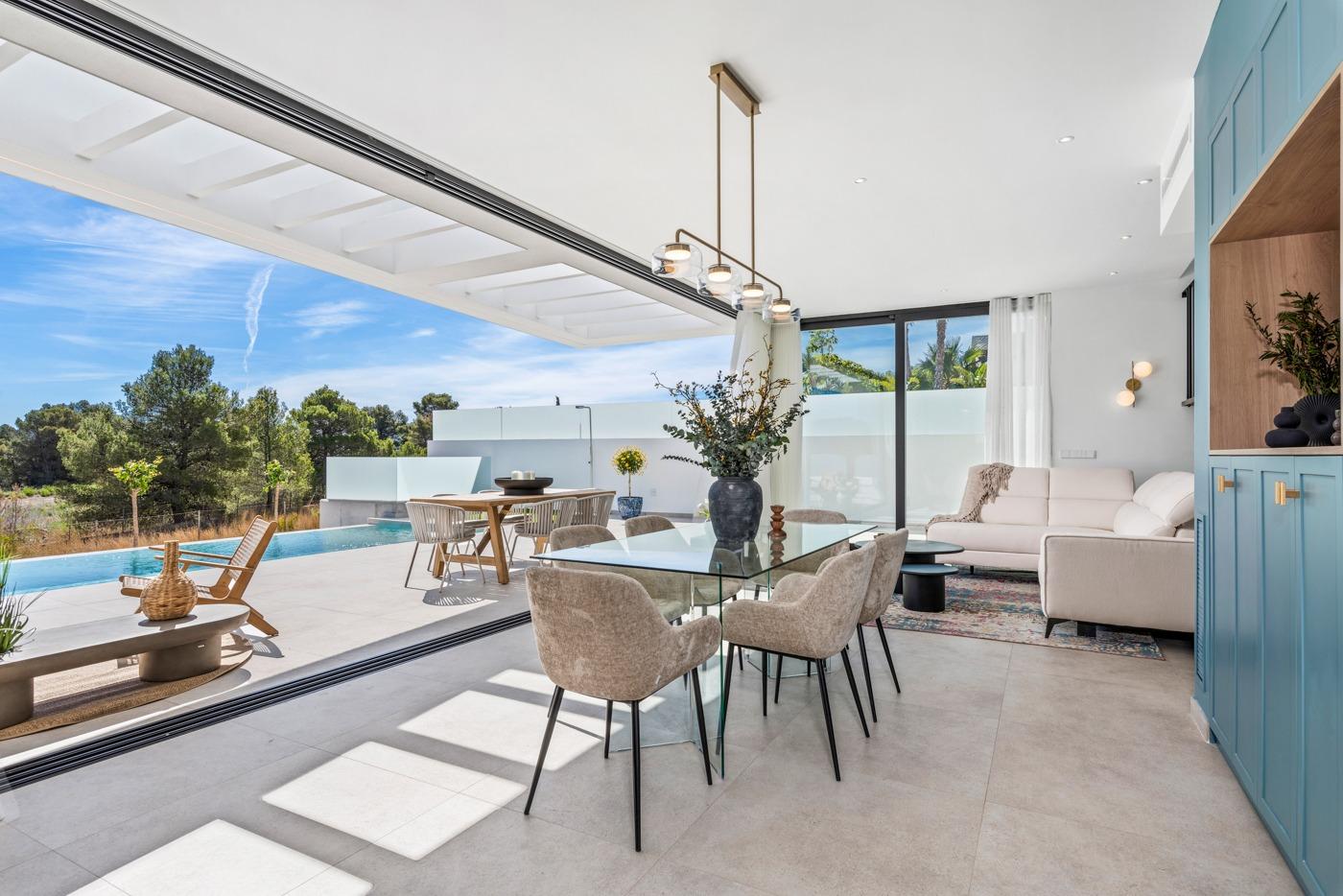 Sun-drenched open-plan dining and living area with modern furnishings and sliding doors opening to private pool terrace in Polop villa.