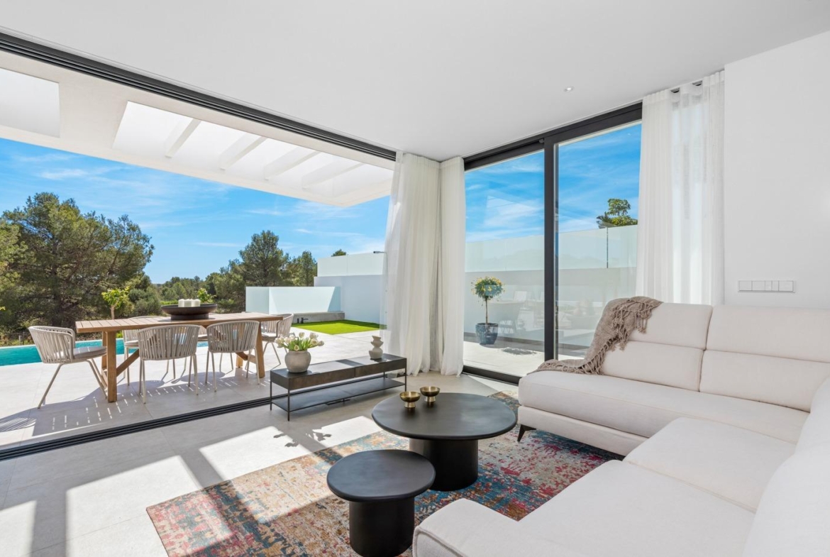 Bright open-plan living area with modern furnishings and large sliding glass doors opening to a sun-drenched terrace and private pool in Polop villa