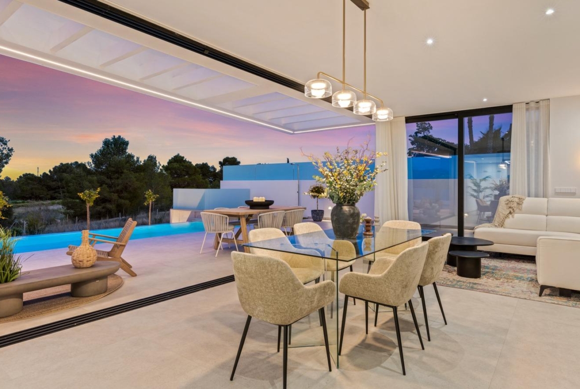 Elegant open-plan living and dining area with glass table, plush seating, and sliding doors opening to a private pool in Polop villa