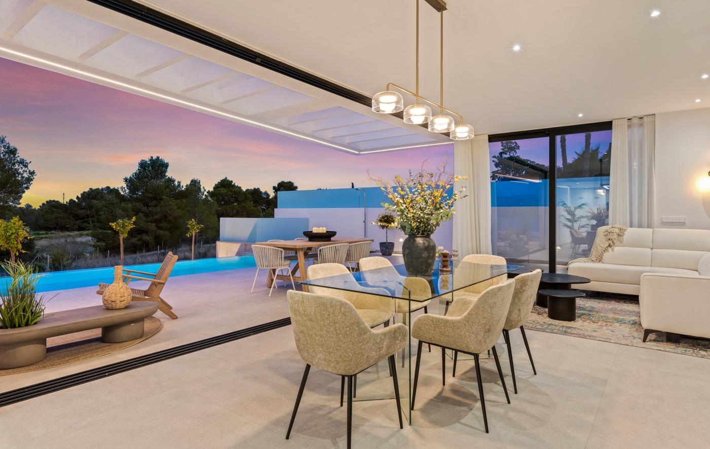 Elegant open-plan living and dining area with glass table, plush seating, and sliding doors opening to a private pool in Polop villa