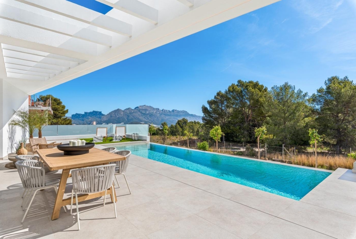 Spacious sun-drenched terrace with elegant dining area and private infinity pool overlooking lush greenery at a 3-bedroom villa in Polop, Costa Blanca