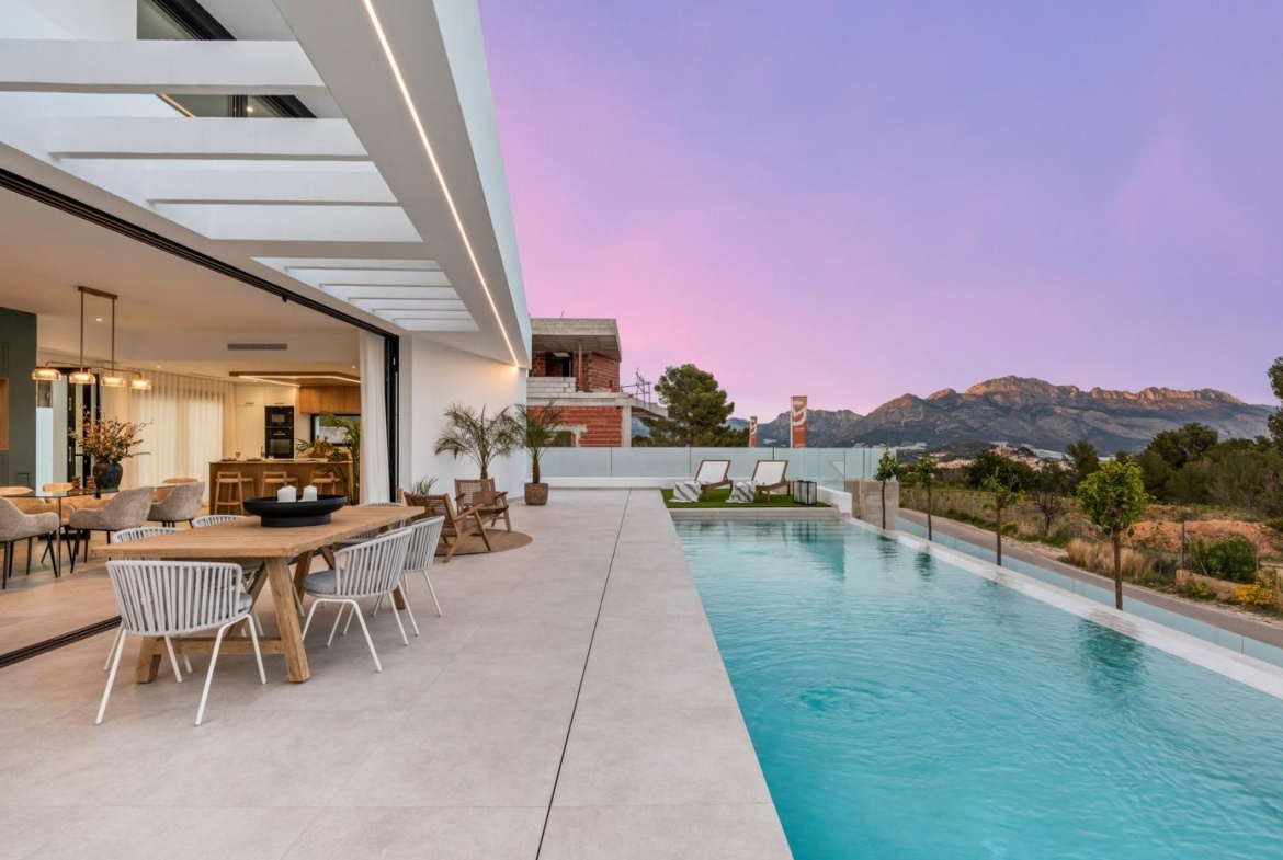Modern 3-bedroom villa in Polop with spacious terrace, sleek private pool, elegant outdoor dining, and panoramic mountain views at sunset.