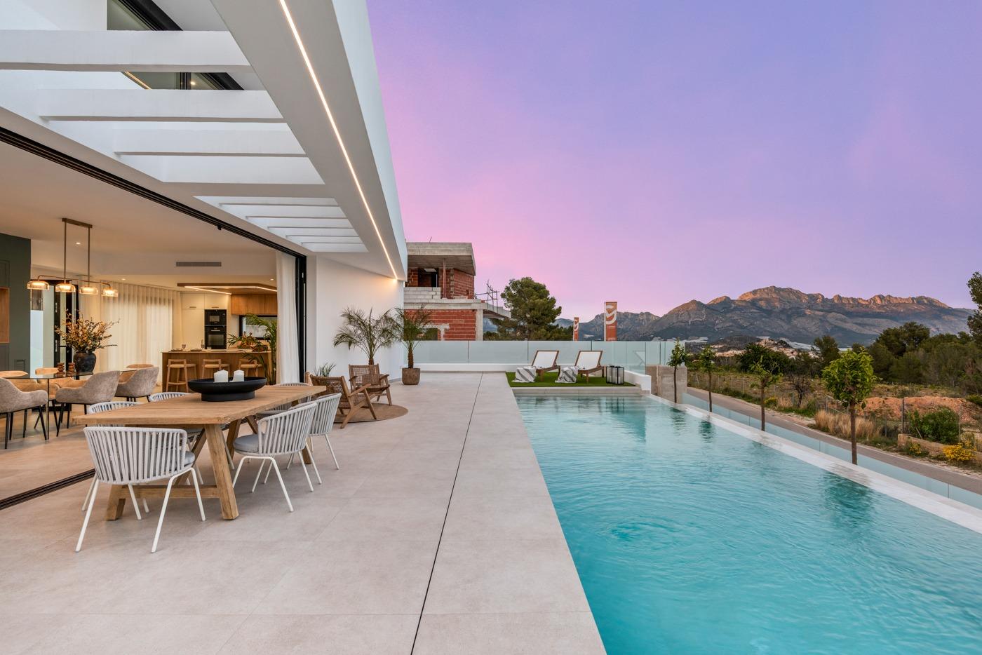 Modern 3-bedroom villa in Polop with spacious terrace, sleek private pool, elegant outdoor dining, and panoramic mountain views at sunset.
