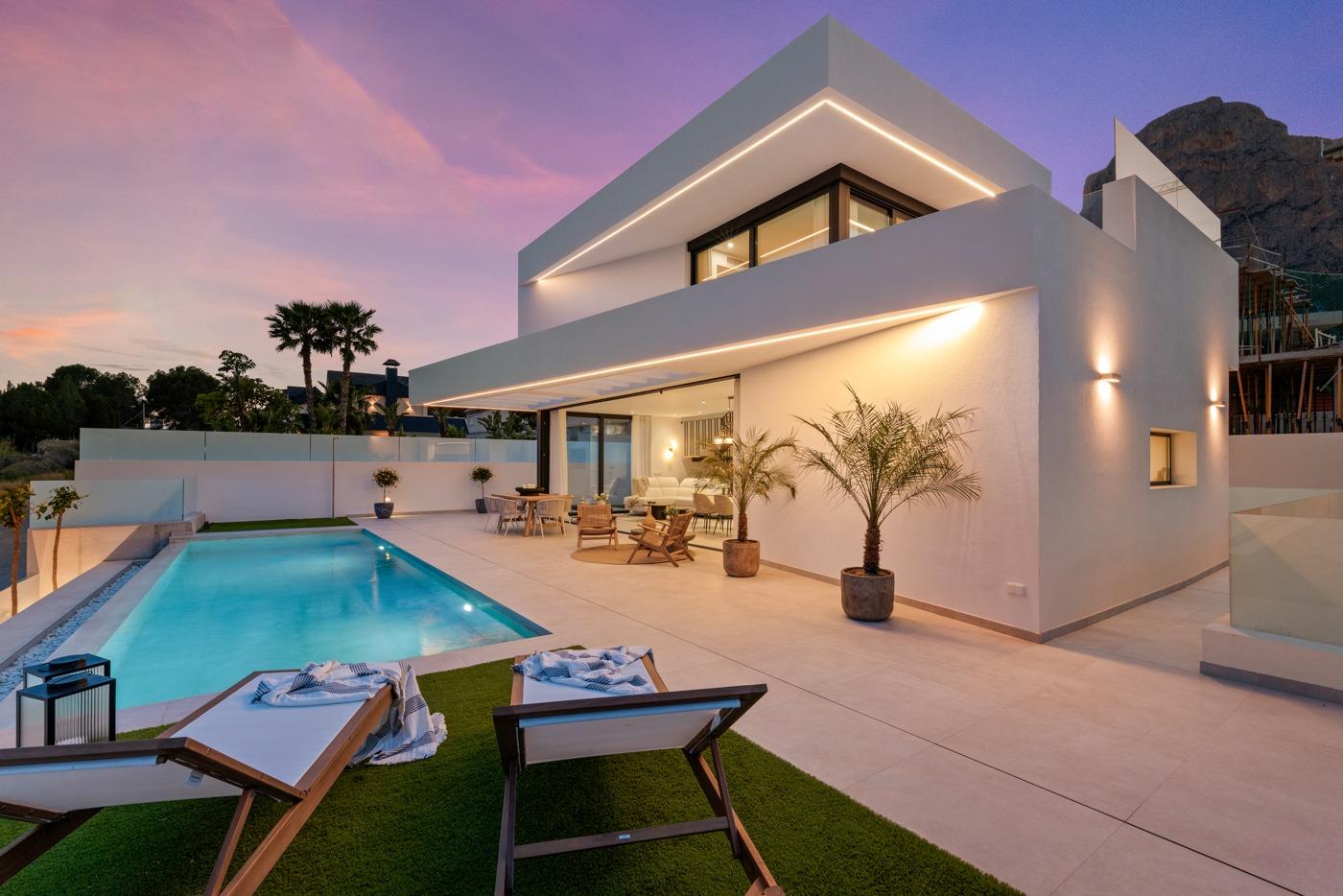 Modern 3-bedroom villa in Polop with private illuminated pool, spacious terrace, and sleek sunset-lit exterior.