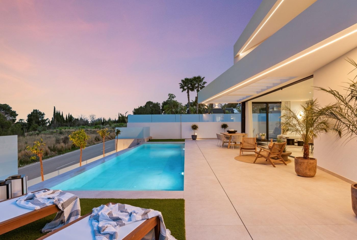 Sunset-lit private pool and sleek terrace of modern 3-bedroom villa in Polop, Costa Blanca with stylish outdoor seating and lush surroundings.
