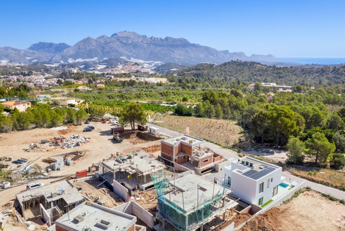 Modern new build 3 bedroom villa under construction with private pool site in Polop, Costa Blanca, surrounded by lush greenery and mountains.