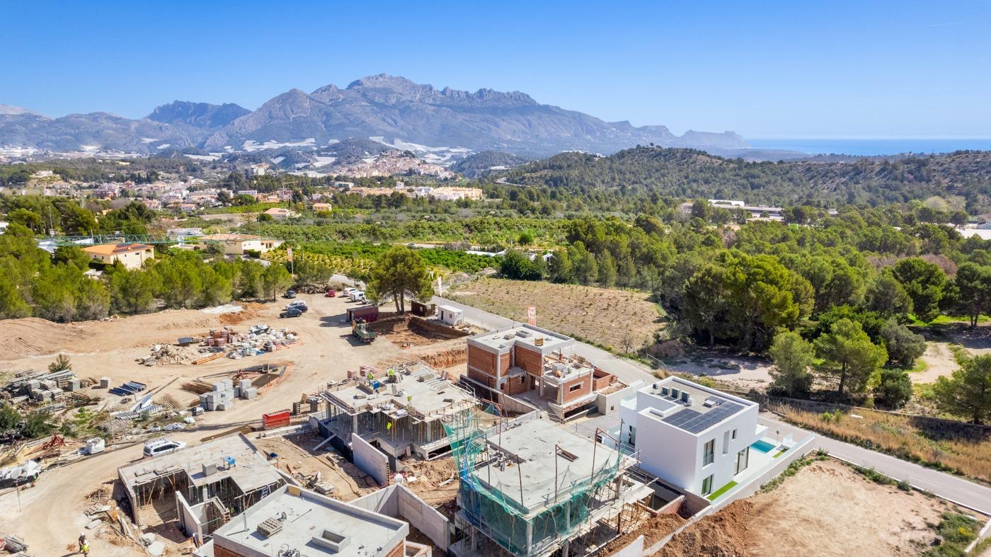 Modern new build 3 bedroom villa under construction with private pool site in Polop, Costa Blanca, surrounded by lush greenery and mountains.