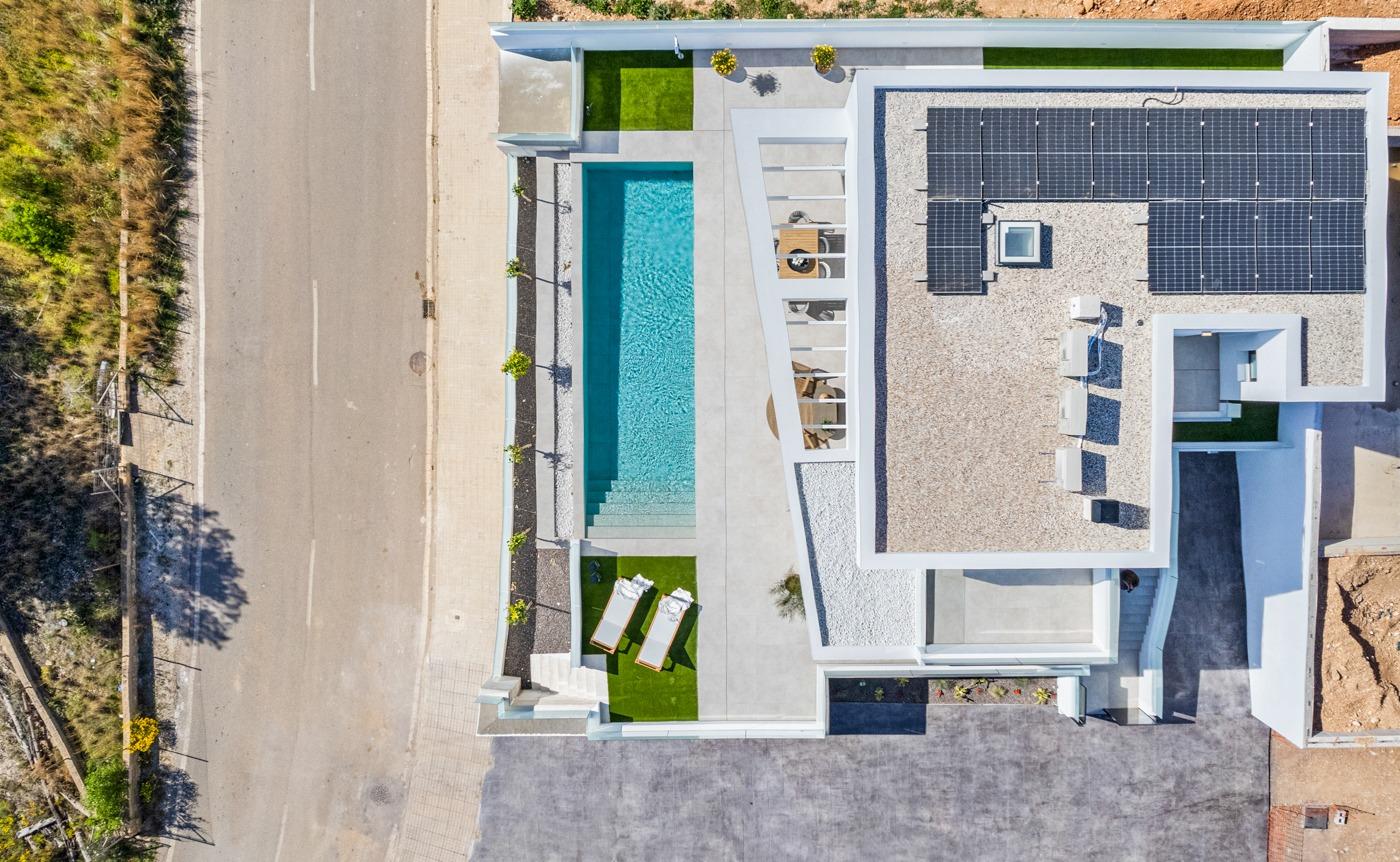 Aerial view of a modern 3-bedroom villa in Polop with a private turquoise pool, sun-drenched terrace, and sleek solar panels