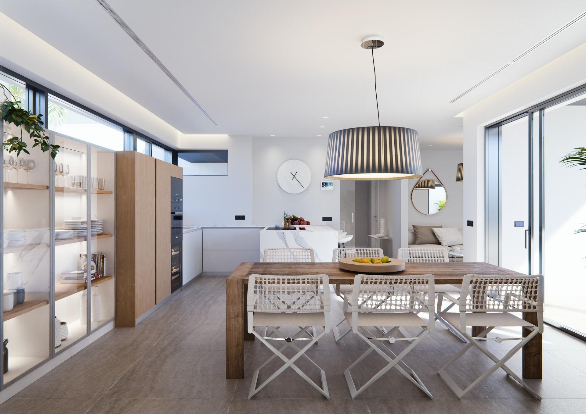 Bright modern dining area and open-plan kitchen with sleek cabinetry in a new built villa on a floor.