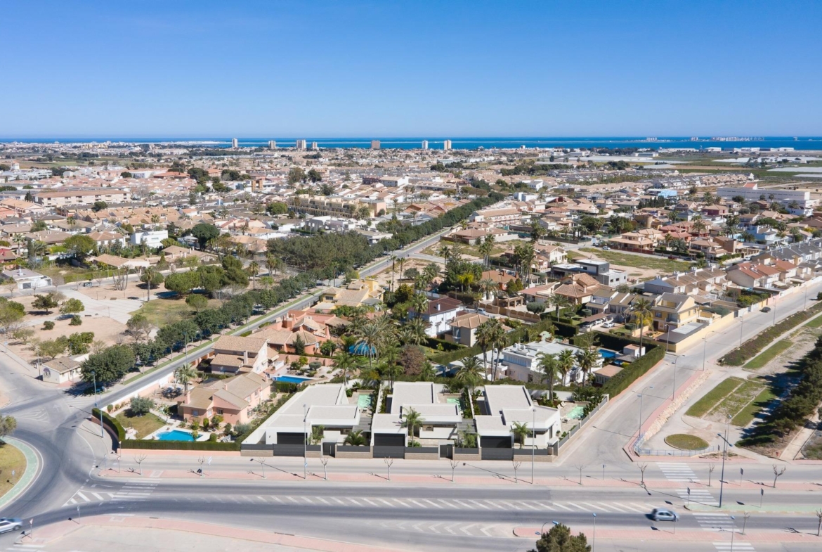 Modern new built villa on a floor with sleek design, private landscaped gardens, and panoramic aerial view of the coastal neighborhood.