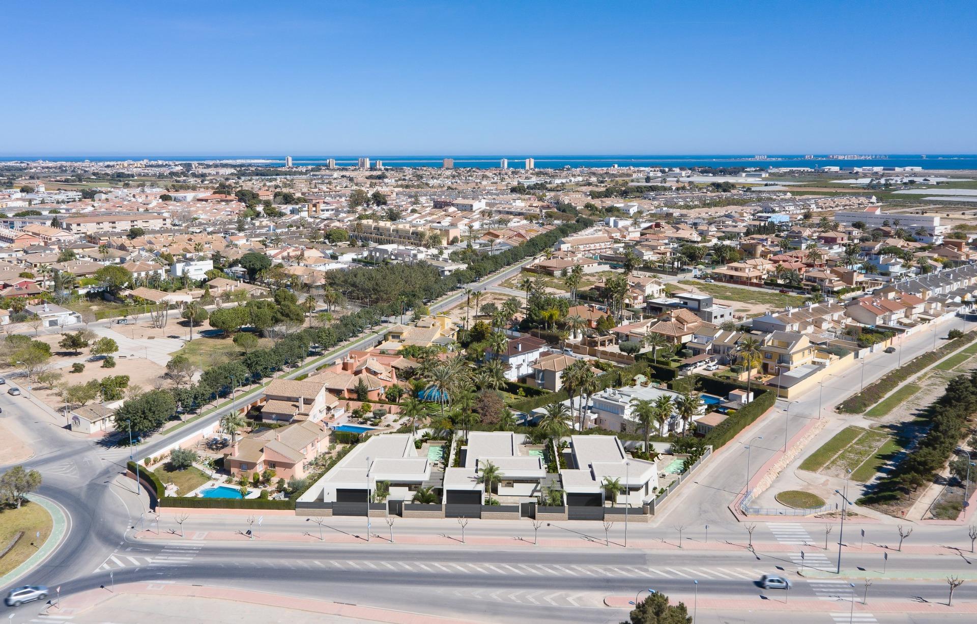 Modern new built villa on a floor with sleek design, private landscaped gardens, and panoramic aerial view of the coastal neighborhood.