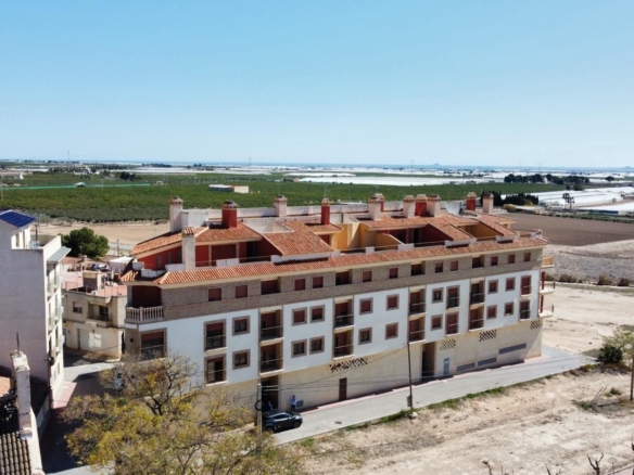 Modern 1 bedroom apartment complex with terracotta roofs surrounded by open fields in sunny Avileses, Murcia.