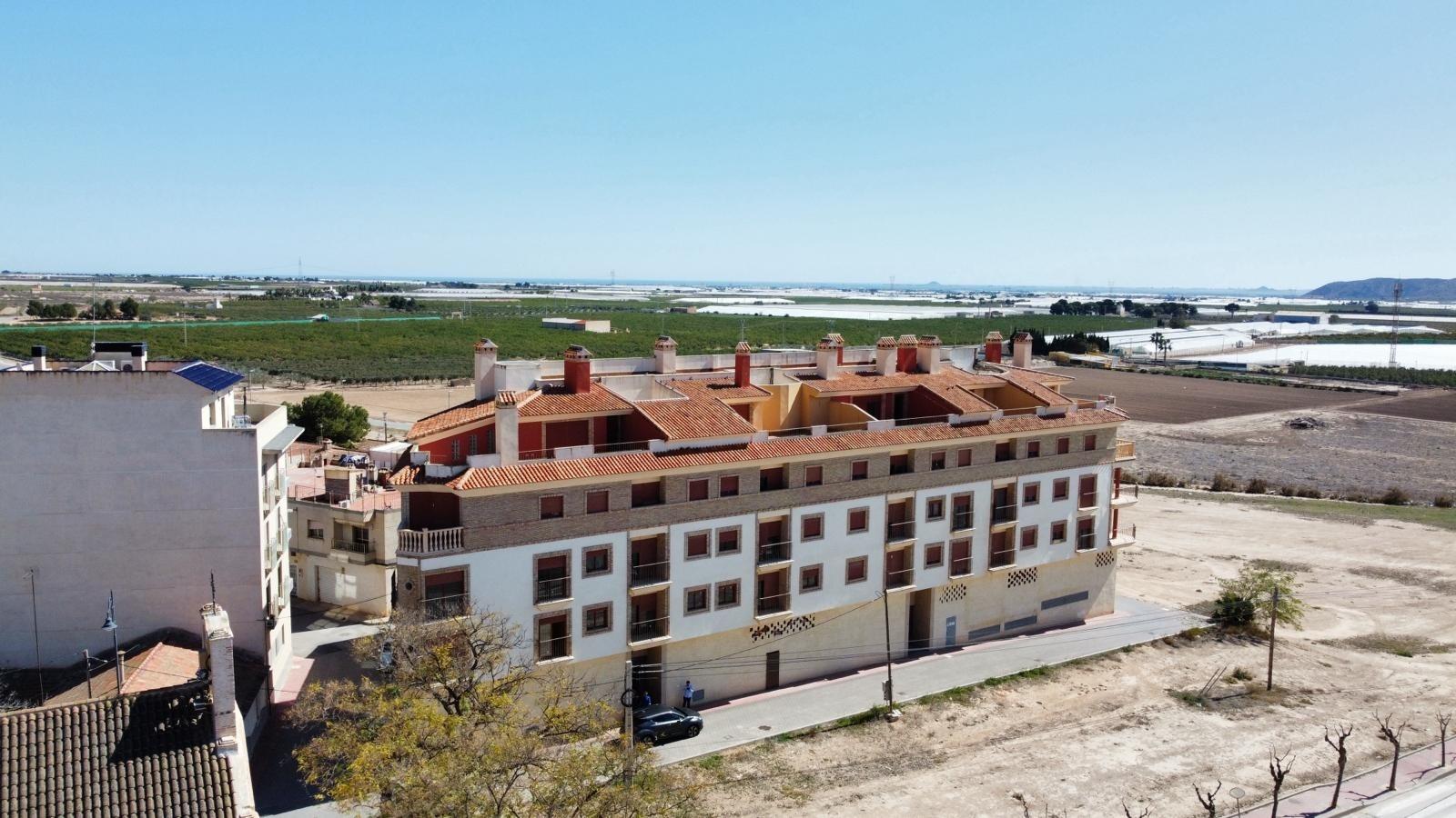 Modern 1 bedroom apartment complex with terracotta roofs surrounded by open fields in sunny Avileses, Murcia.
