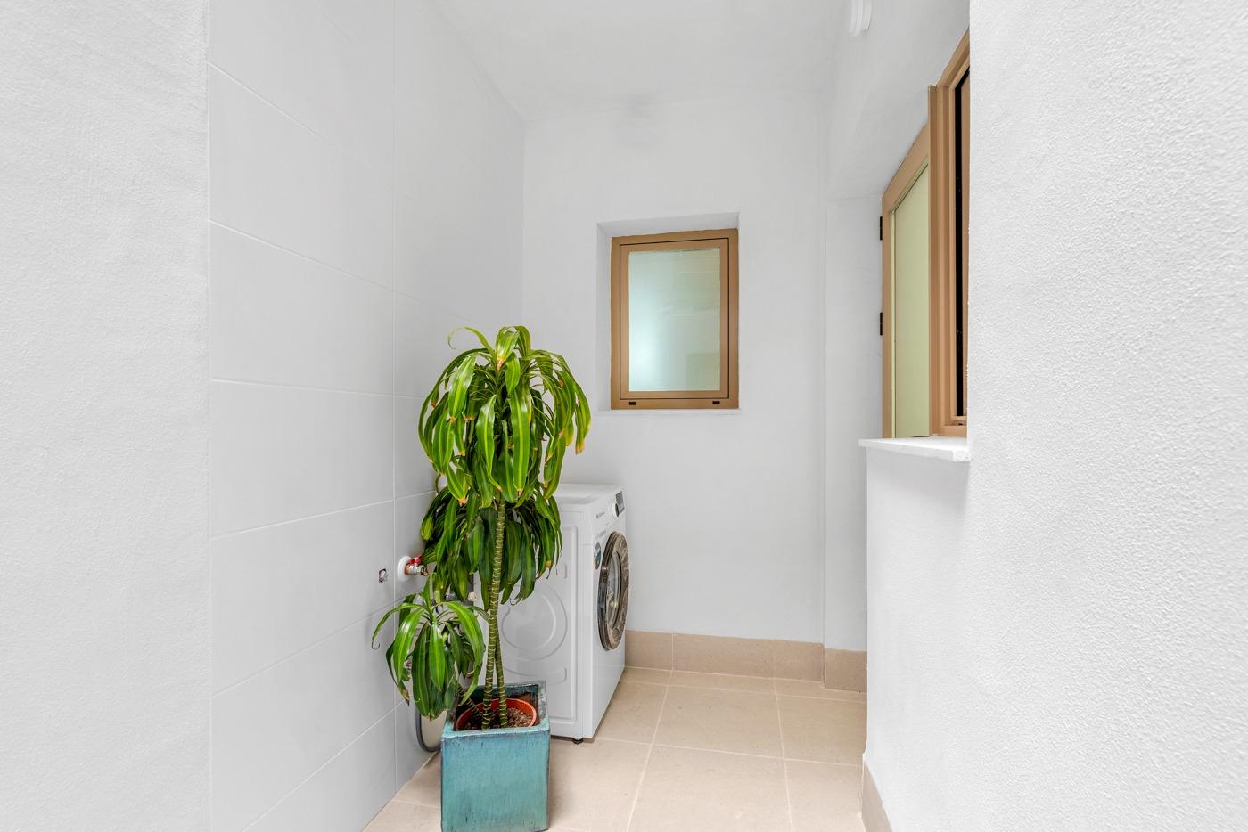 Bright, modern utility area with washer, potted plant, and tiled flooring in a new build 3-bedroom ground floor apartment in Jacarilla.