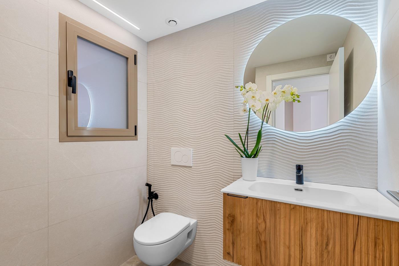 Bright modern bathroom with textured walls and wooden vanity in a 3-bedroom apartment with open views in Jacarilla